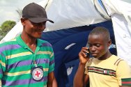 宁巴州，卡恩普莱难民中转营，科特迪瓦难民巴西勒是一名无人陪伴的儿童，他正在往科特迪瓦打电话，打听母亲的下落。红十字国际委员会寻人工作者阿尔贝•谢尔登在一旁静静地听着。