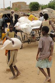 Pessoas chegam com os seus pertences a um abrigo para deslocados em Bagoundjé, próximo a Gao, depois de uma distribuição de alimentos e de garrafas de óleo.