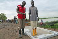 Um voluntário da Cruz Vermelha do Sudão do Sul supervisa uma ducha para pés no porto de Kodok. O CICV e a Cruz Vermelha do Sudão do Sul construíram estas duchas, torneiras para lavar as mãos e banheiros nas áreas mais expostas ao cólera, para prevenir a disseminação da doença.