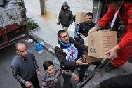 Сирия, Хомс. Местные жители помогают добровольцам Сирийского Арабского Красного Полумесяца разгрузить ящики с продовольствием.