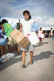 Guiuan: una joven mujer se va del sitio de distribución con una caja que contiene artículos esenciales. Varios centros de evacuación que albergan a personas desplazadas por el tifón se sitúan en Guiuan.