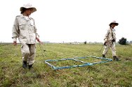 في حقول مُقاطعة شيانغ خوانغ, إحدى فِرق إزالة الألغام تستخدم جهازًا للكشف عن الذخائر غير المنفجرة والأجسام المعدِنية الأخرى.
