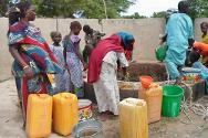 نساء يملأن الأوعية بالمياه النقية عند أحد الآبار التي جددتها اللجنة الدولية. وقد أدى تدفق السكان الفارين من نيجيريا إلى نقص في المياه واضطر بعض الناس لشرب المياه الراكدة رغم المخاطر الصحية الهائلة.