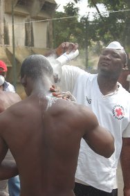 阿比让，拘留惩教所，一名红十字志愿者帮助一名被拘留者除虫。