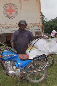 利比里亚，大吉德州，科特迪瓦难民开着摩的帮助人们从红十字国际委员会分发点往各个村庄运送援助物资。