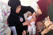 红十字国际委员会医疗工作代表正在为来自纳杰夫库法一个流离失所家庭的孩子检查身体。