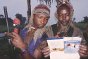 Photo, Young militiamen in Sierra Leone looking at a brochure that explains the role and nature of the emblems.