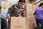 Homs, Syria. SARC volunteers and members of the local community unload trucks of humanitarian assistance.