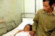 Laos. Un padre observa a su hija, herida por submuniciones; la madre y un hermano de la joven también sufrieron heridas, y otro hermano murió.