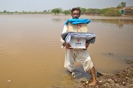 Pakistán. Mohammad Saleem regresa a su casa dañada a través de un campo inundado, llevando consigo una batería de cocina, sábanas y mosquiteros. Su pueblo fue duramente golpeado por el monzón que comenzó el 9 de agosto de 2011.