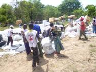 Kipia, provincia de Katanga, en el territorio de Malemba-Nkulu. Durante una distribución del CICR, una beneficiaria recoge su paquete de socorros con la ayuda de un voluntario de la Cruz Roja de la RDC.