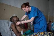 Una enfermera de un equipo quirúrgico brinda atención post-operatoria a un hombre herido por los combates.