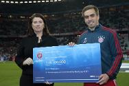 Allianz Arena, Múnich, 11 de marzo de 2014. Philipp Lahm y Charlotte Lindsey-Curtet, directora de Comunicación del CICR, sostienen el cheque donado por 100.000 euros.