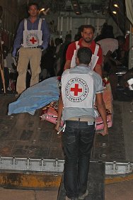 Aéroport de Koufra, Libye. Des membres du CICR chargent un blessé à bord d'un avion qui le conduira à Tripoli, où il sera hospitalisé.