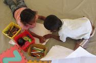 Des enfants dessinent à l’intérieur de la tente dédiée au soutien psychosocial.