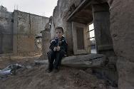 Al Qasir. Un enfant assis dans les décombres d'une maison.