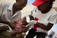 Haiti, Port-au-Prince. Haitian Red Cross volunteers give first aid to a child at a first-aid post set up by the ICRC.
