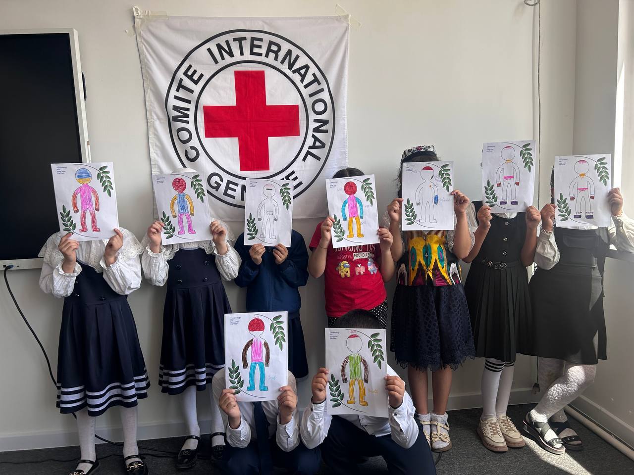 Children during an ICRC focused psychosocial support session hold up “body-mapping of emotions” drawings