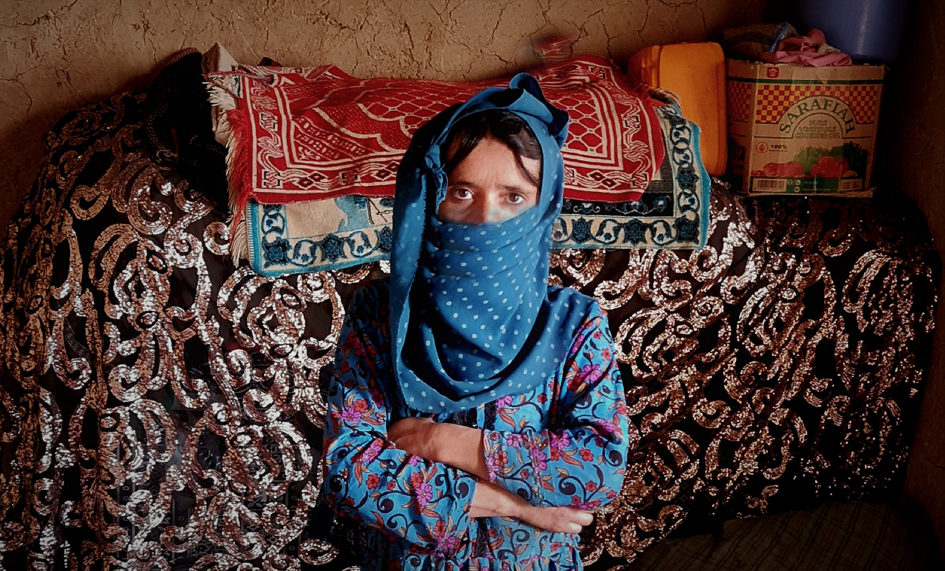 A woman in burqa faces the camera with her arms crossed in front of her chest.