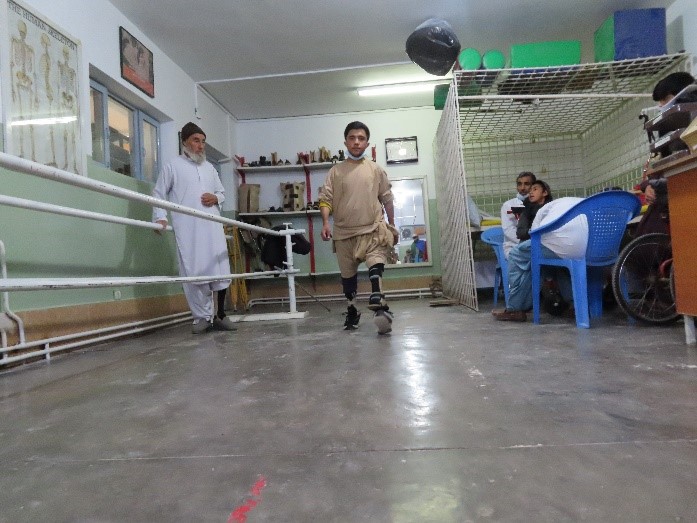 A boy with physical disability walks as other people watch.