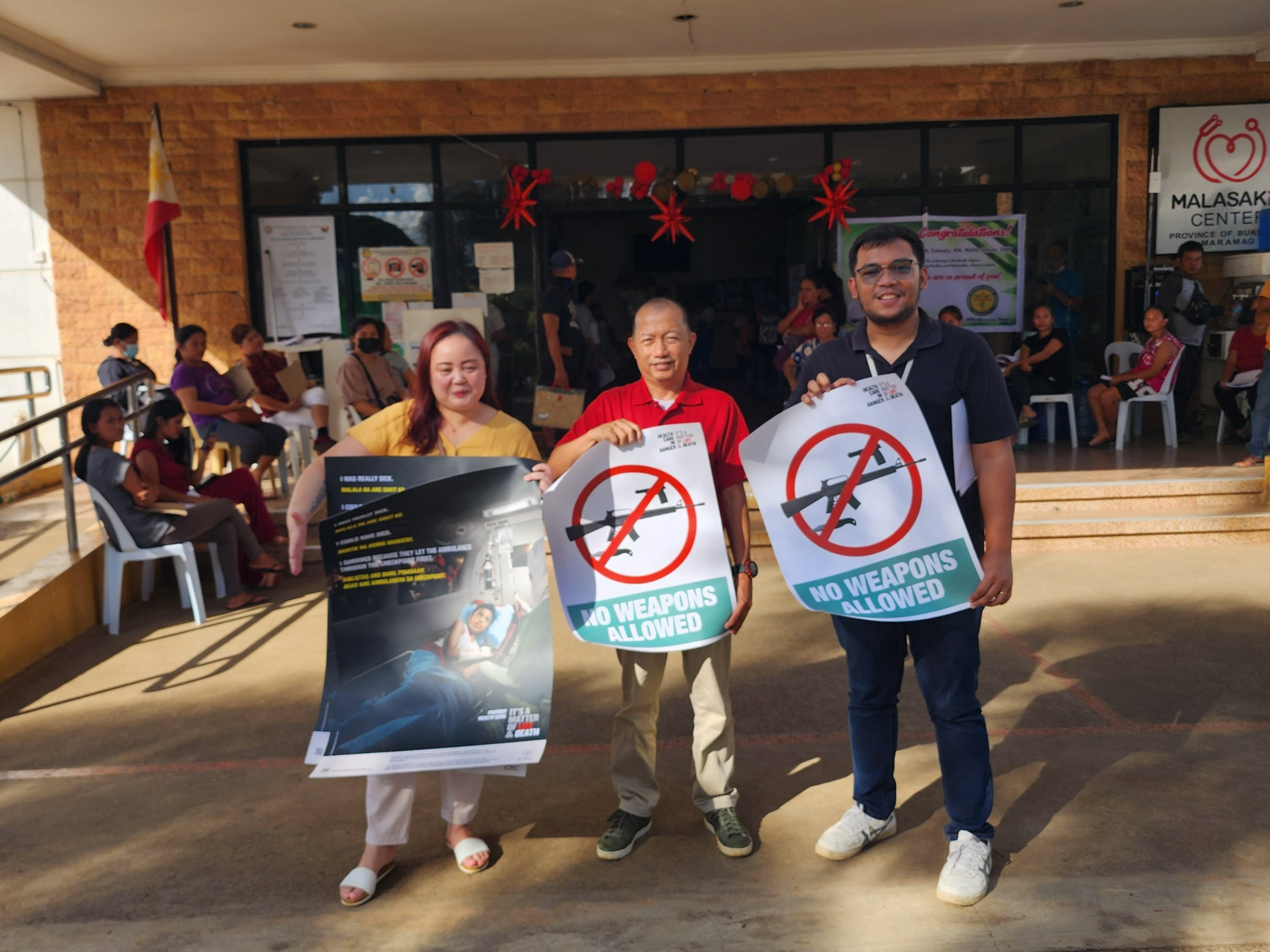ICRC health field officer Erik Precillas (right), hands over violence prevention posters to Dr. Edmundo Garcia (center), Medical Center Chief of Bukidnon Provincial Hospital, and nurse Katrina Atay (left) in Maramag, Bukidnon. Photo: ICRC.