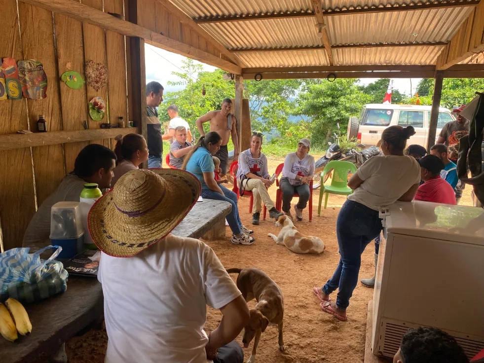 Personas de una comunidad rural en Colombia están sentadas en grupo mientras conversan con representantes del Comité Internacional de la Cruz Roja (CICR), en un entorno comunitario.
