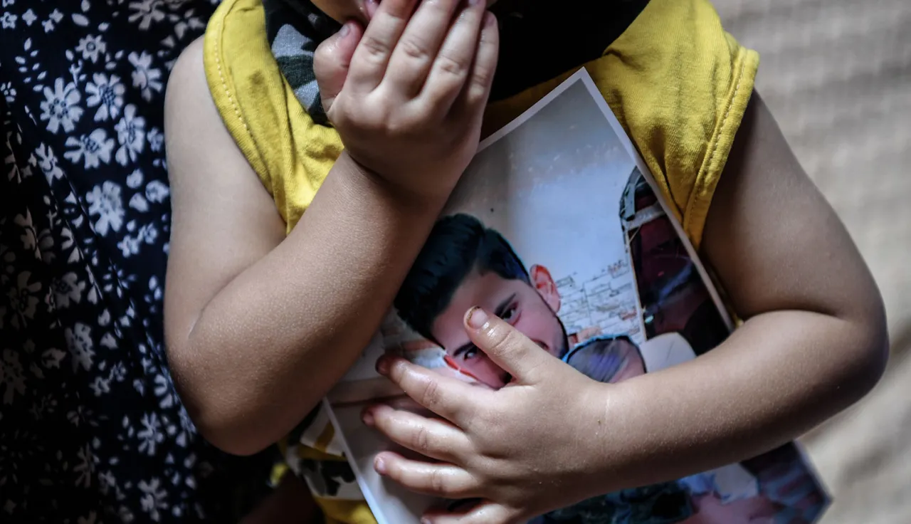 Child holds picture of missing family member. 