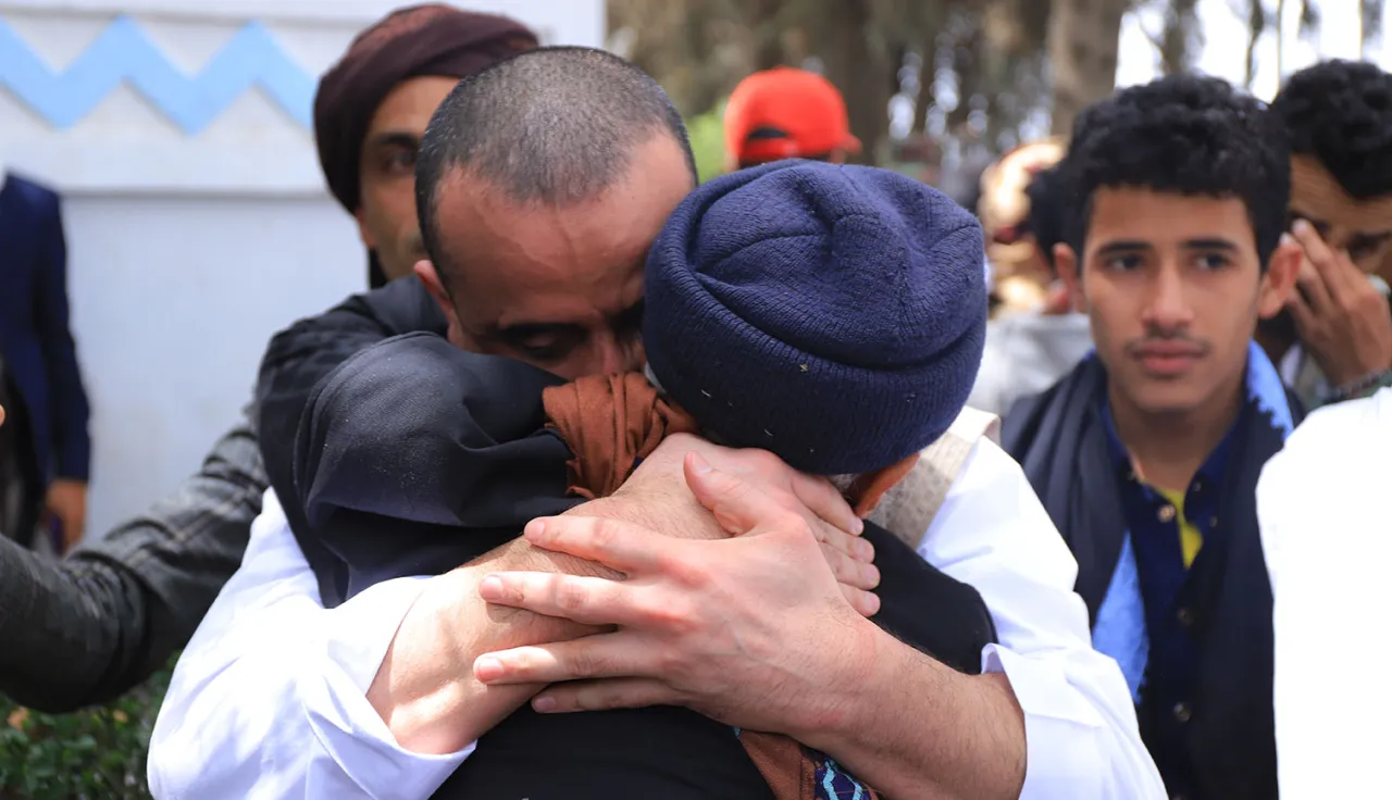 People embrace and shed tears during a prisoner release operation in Yemen, facilitated by the ICRC as a neutral intermediary.