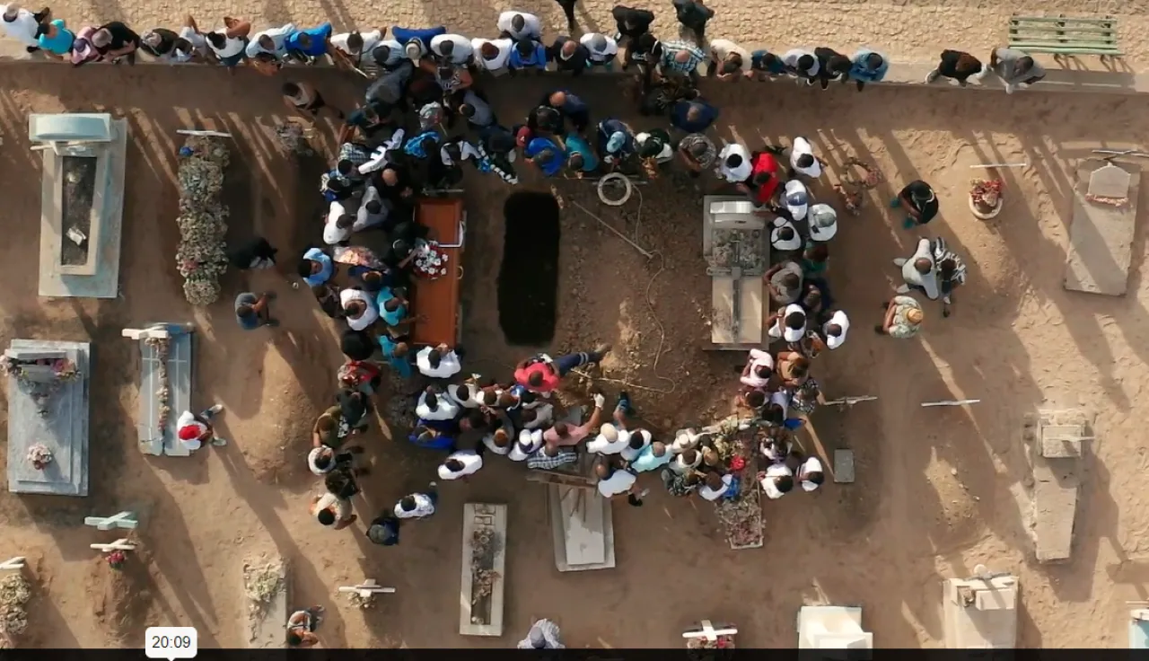 Funeral burial taking place in an African cemetery Group of people gathering around a coffin that will be buried