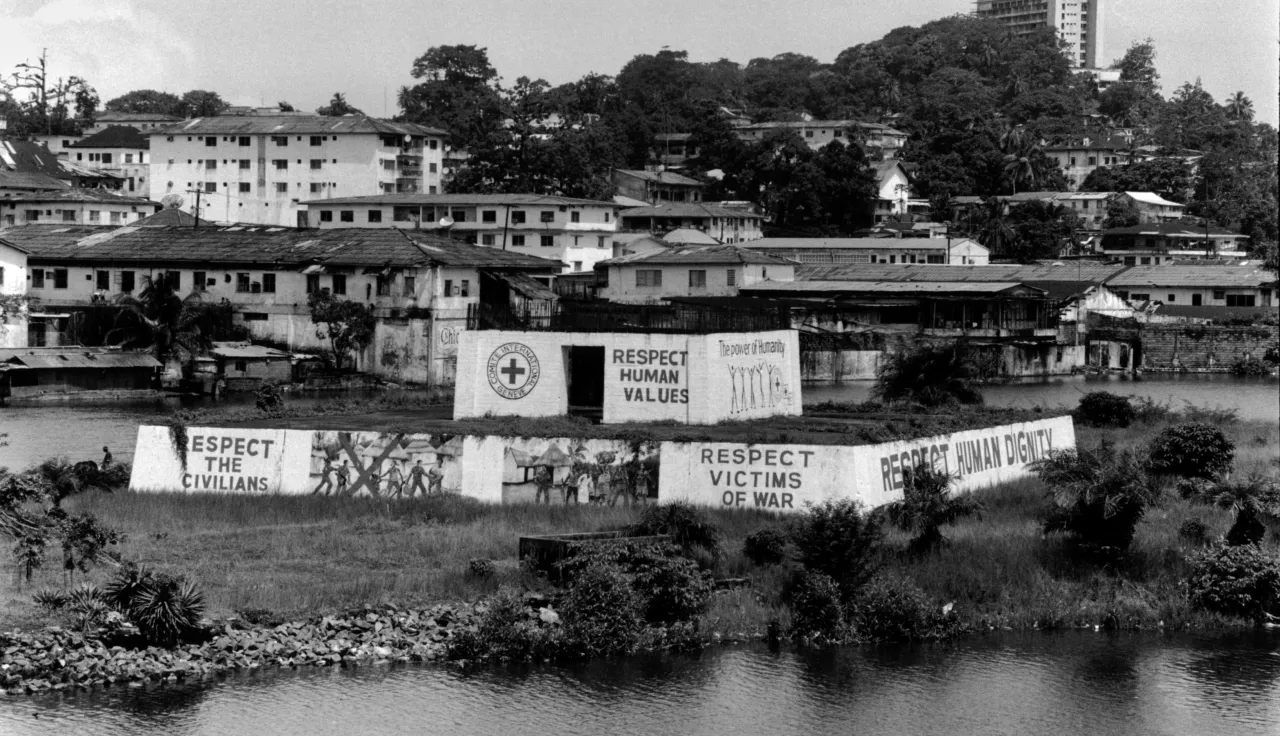 Cidade com paredes pintadas com uma cruz vermelha e textos que dizem "Respete os civis", "Respeite os valores humanos", "Respeite as vítimas da guerra" e "Respeite a dignidade humana".