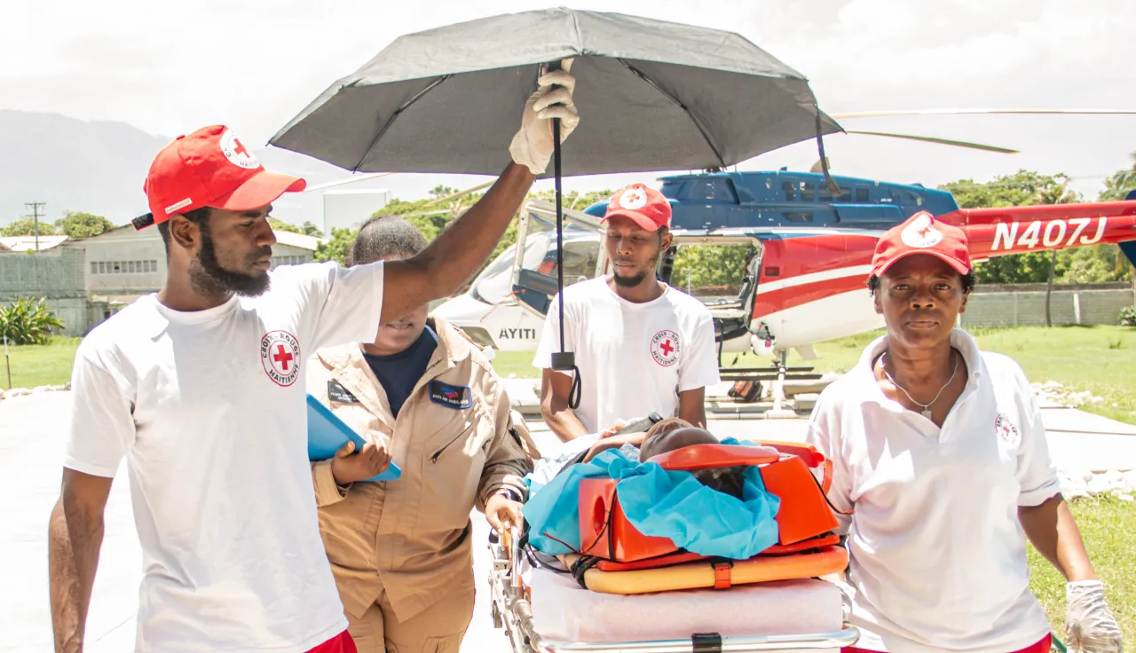 ICRC Haiti. Photo: Jean Jacob Charles Ambulance workers shield a patient on a stretcher from the sun with an umbrella