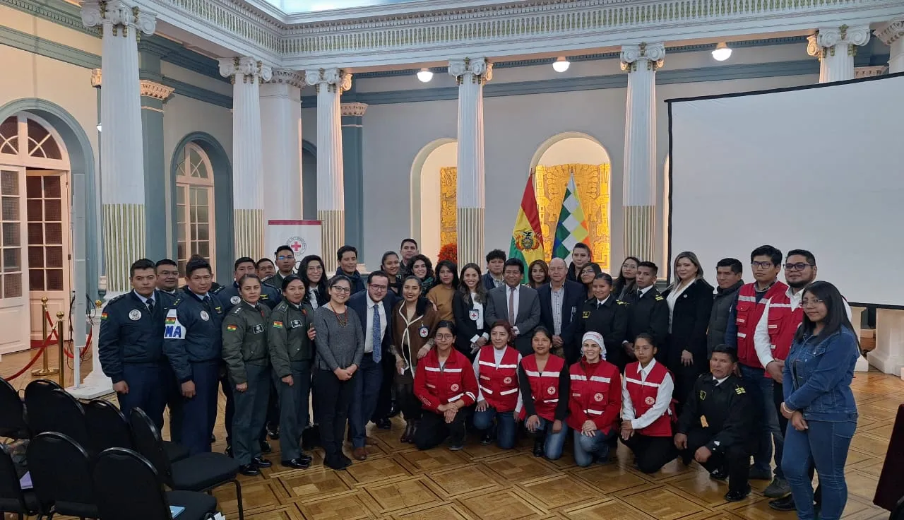 Mariscal Andrés de Santa Cruz Bolivia CICR Policías, militares y otros funcionarios con miembros del Movimiento de la Cruz Roja posan para una foto grupal en un salón.
