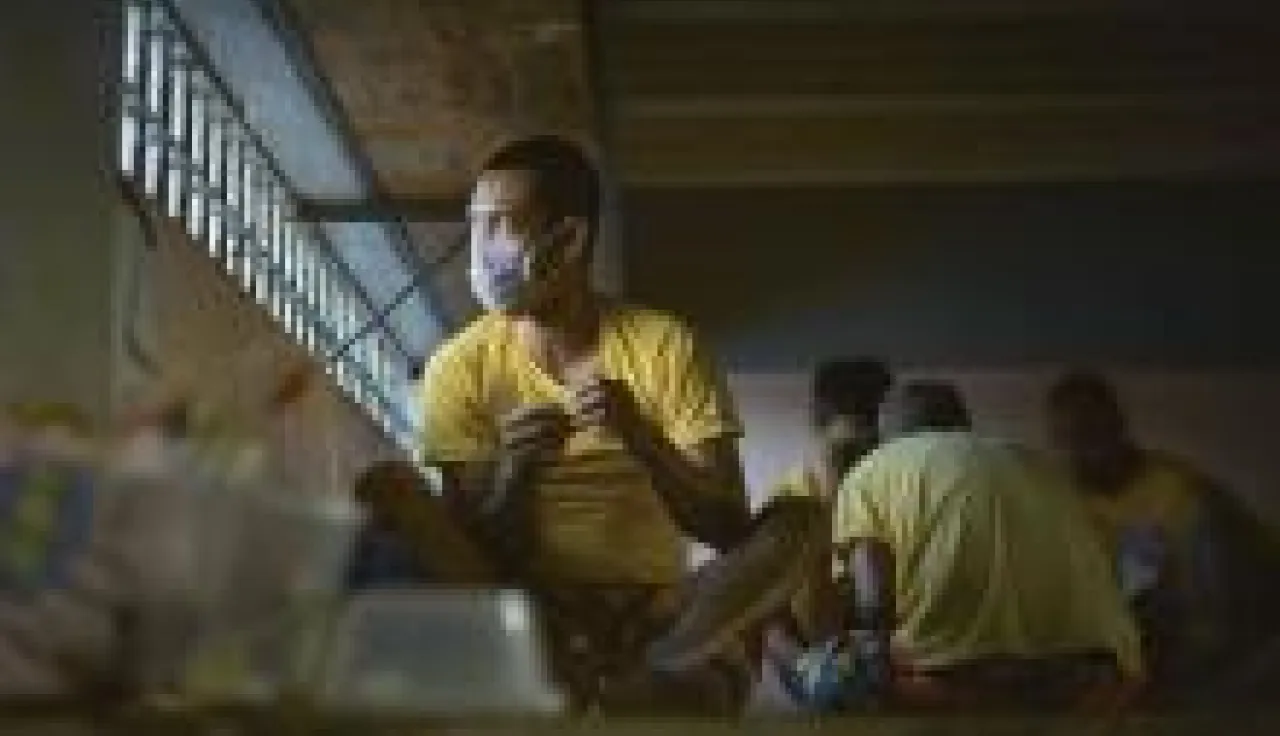 Un hombre con tapabocas mira a través de una ventana.