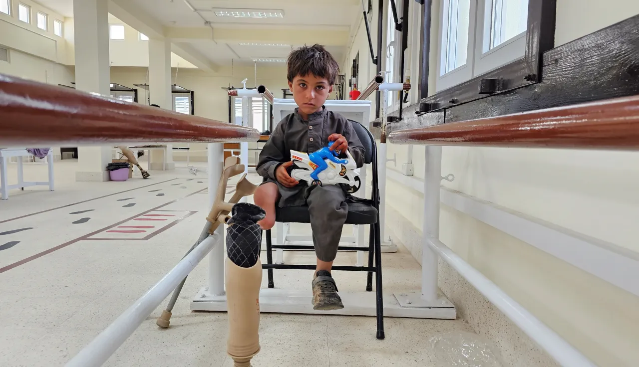 Garçon assis sur une chaise dans un centre de réadaptation du CICR, avec une prothèse de jambe au premier plan