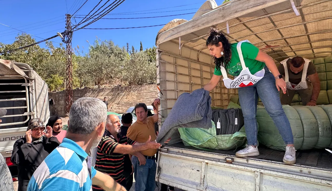 ICRC worker stands at the back of a lorry to unload blankets and essential items