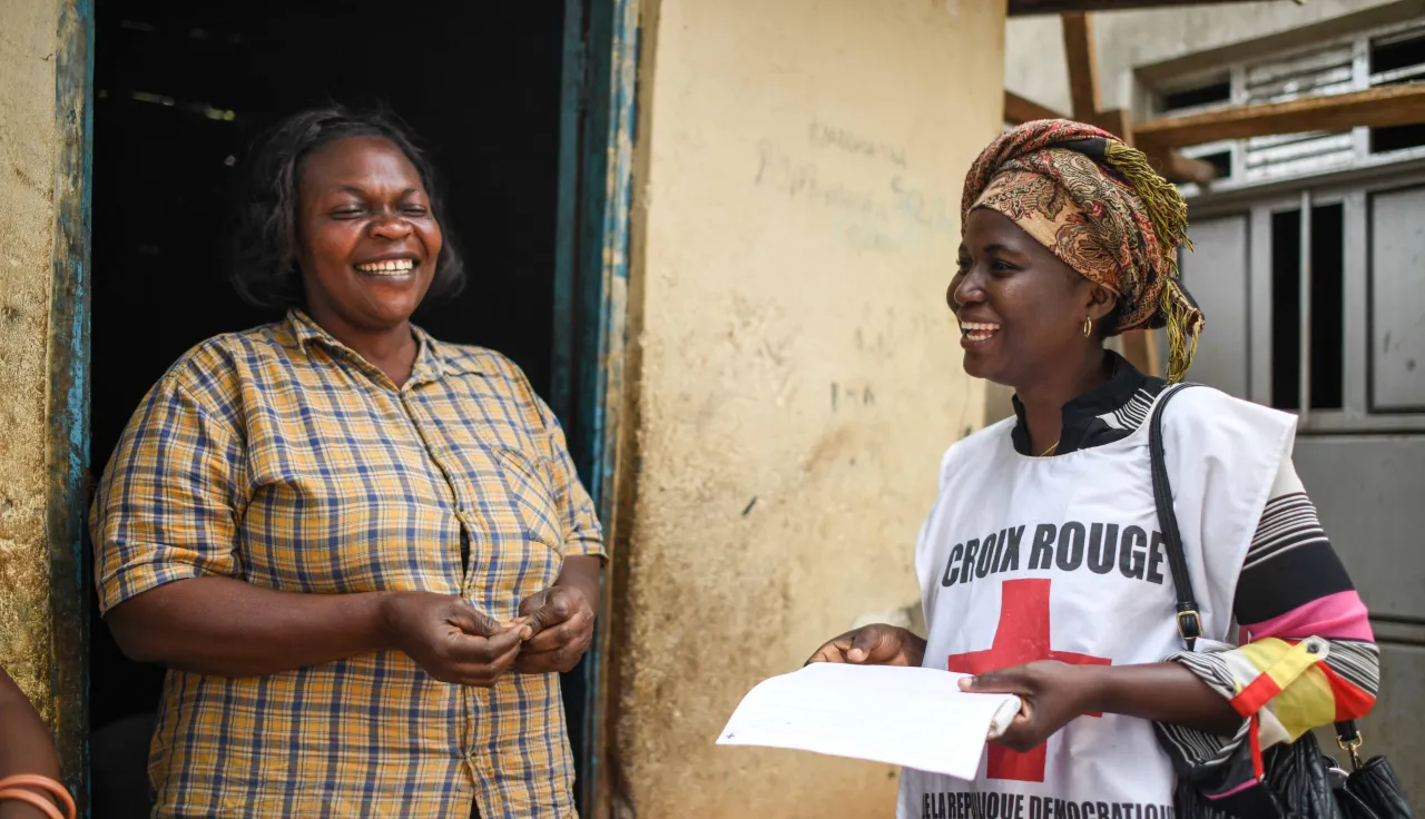 ICRC delegate speaking to a smiling woman in a doorway