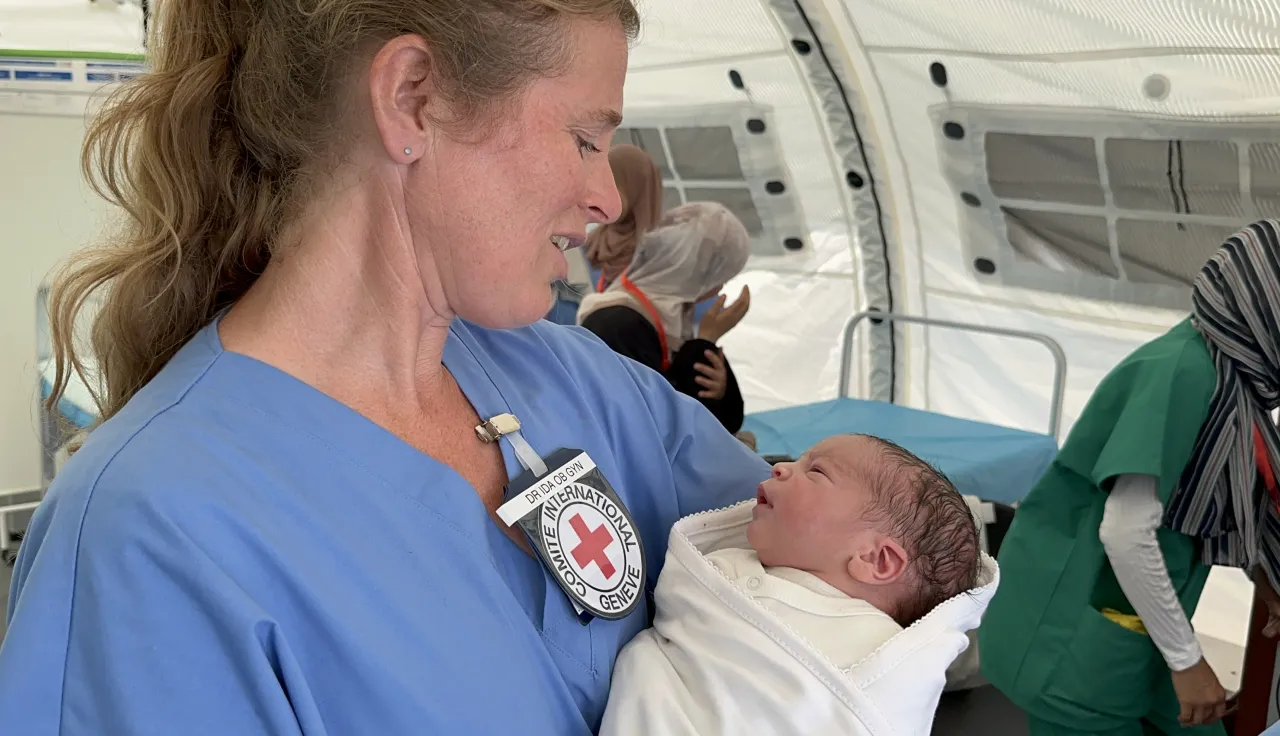 An ICRC nurse holding a newborn in her arms.