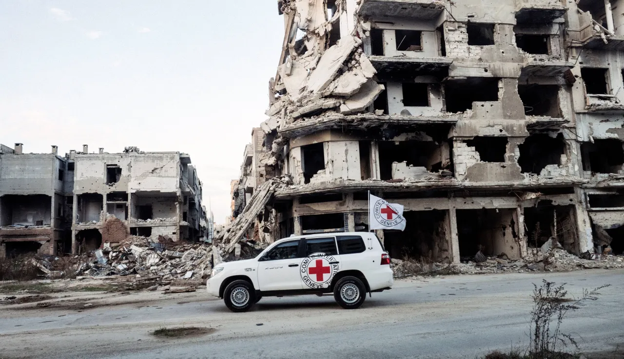 ICRC land cruiser in Homs, Syria, driving past a collapsed building
