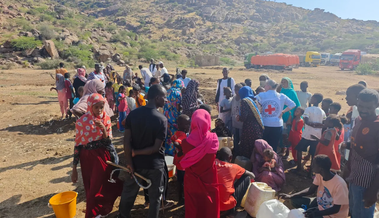 ICRC staff assist displaced families gathering for aid distribution in a rural, mountainous area, in Port Sudan.