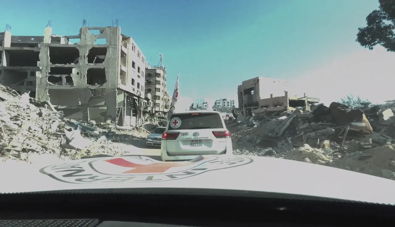 ICRC Landcruisers driving past fallen buildings