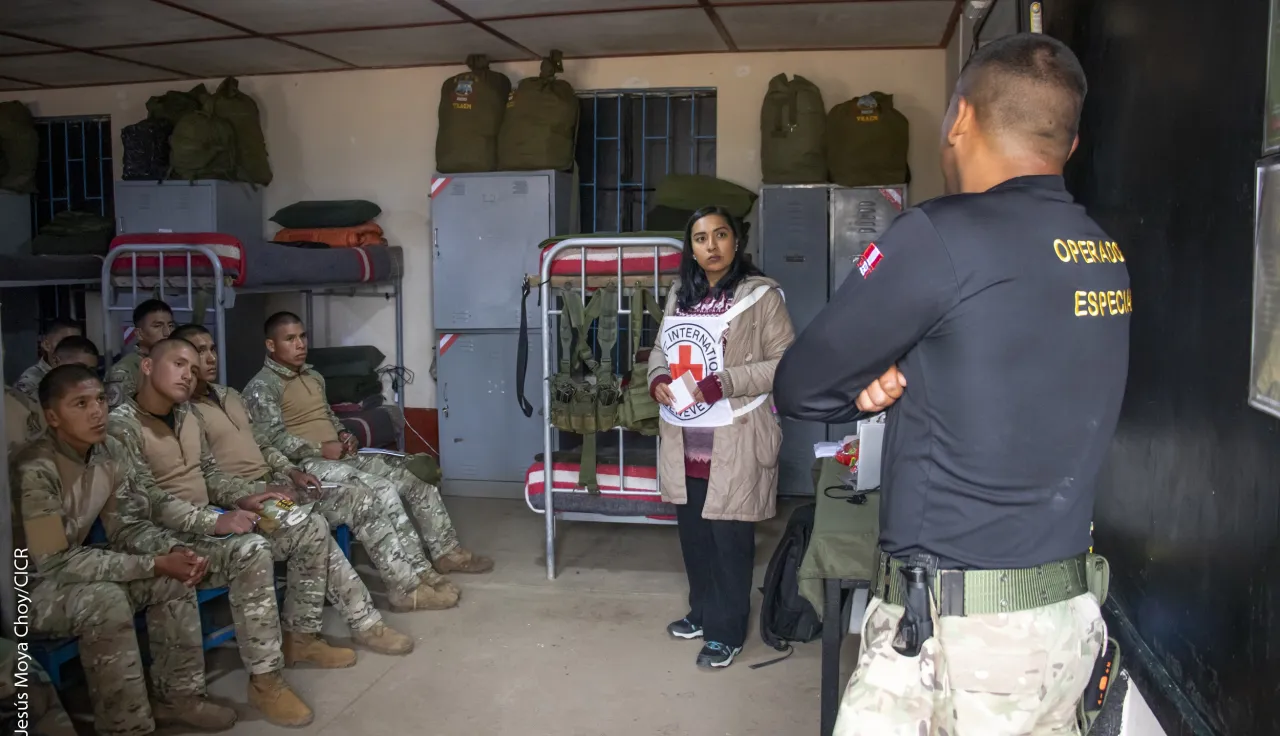 Una trabajadora del CICR explica el DIH a personal militar en un cuarto de tropa.
