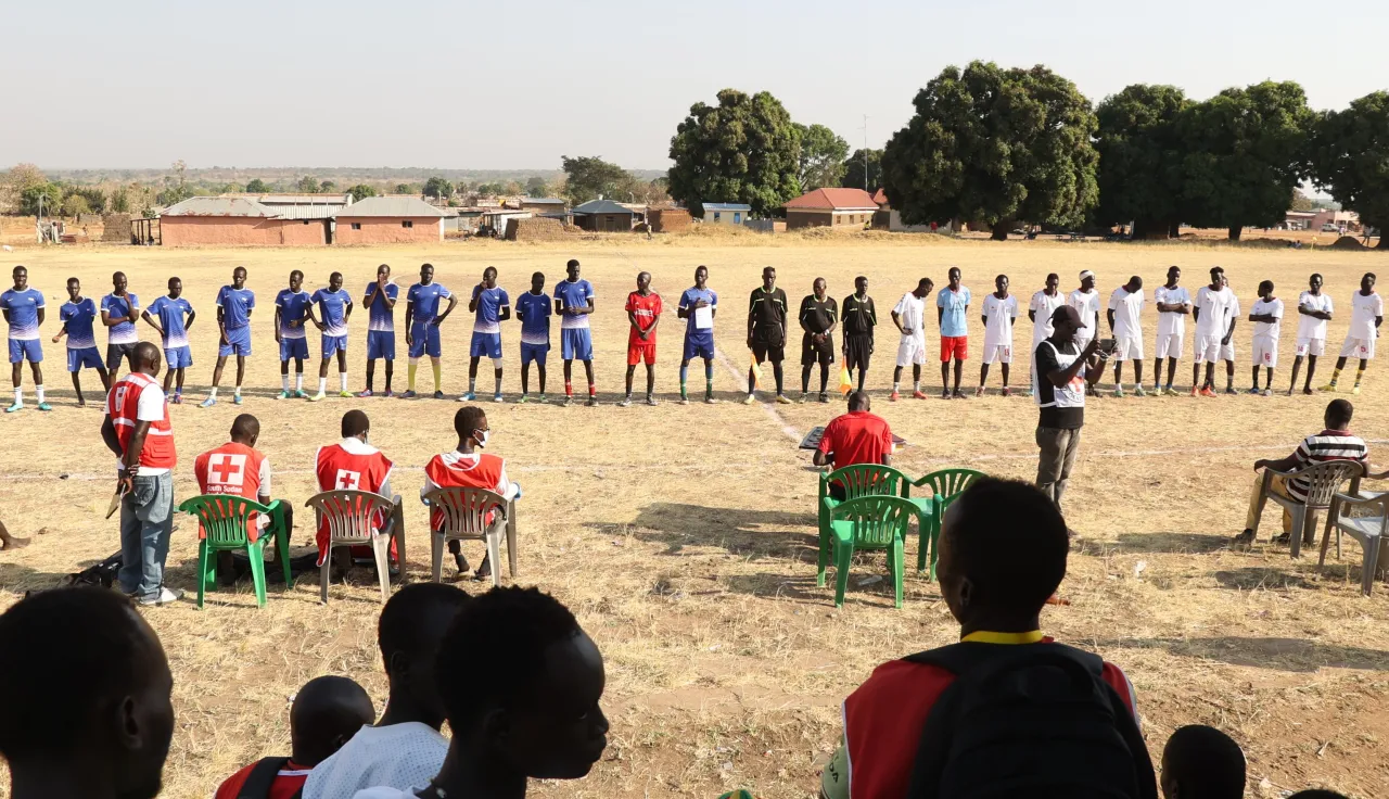 The Downtown and Blue Star football teams line up before kickoff. Photo: Junior Ali/ICRC