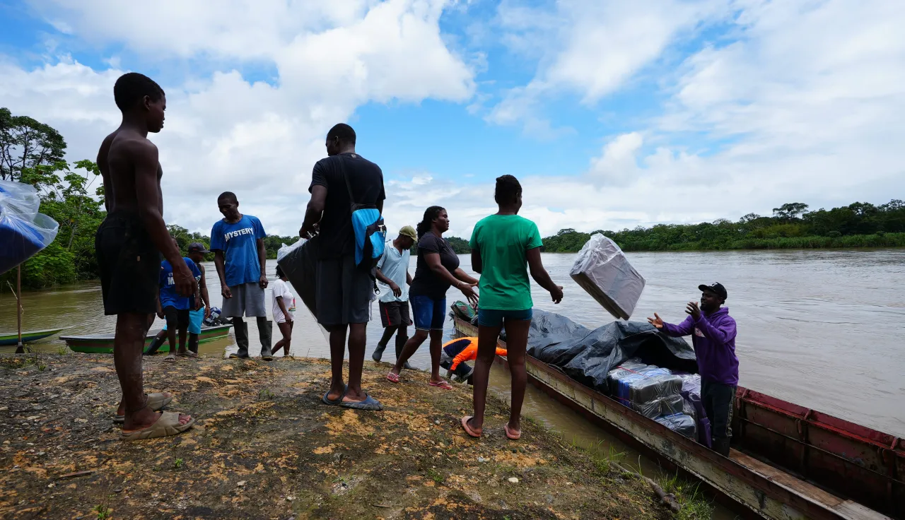 Varias personas están llevando paquetes hacia una lancha.