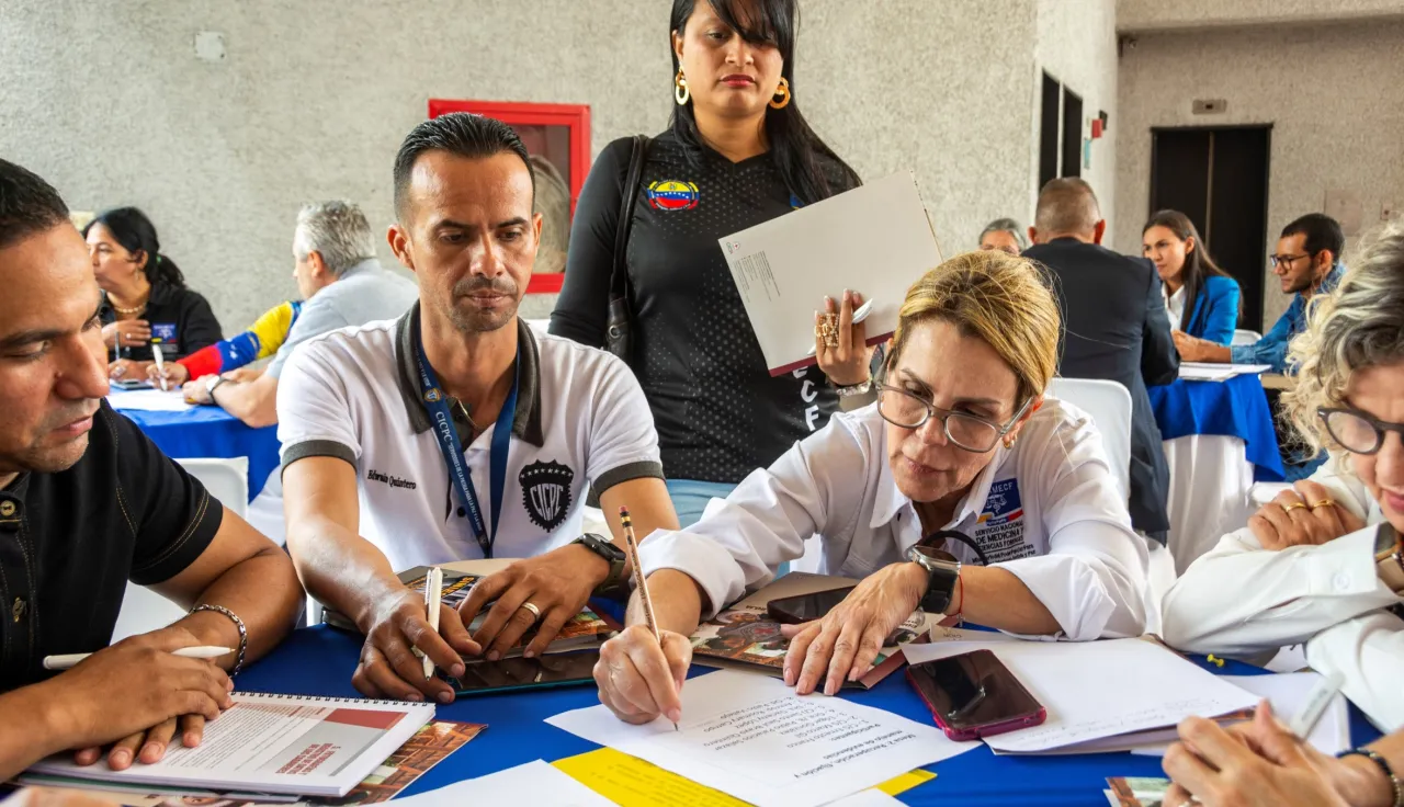 Durante la Jornada Forense organizada por el CICR, varios representantes de instituciones del país están al rededor de una mesa realizando un estudio de caso.