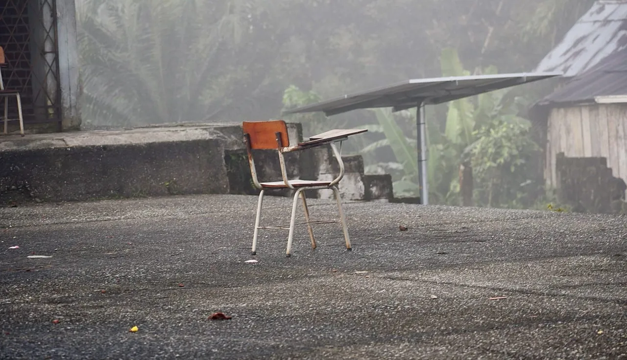 Una silla en medio de un patio, como abandonada, y atrás se ve un contexto de zona rural