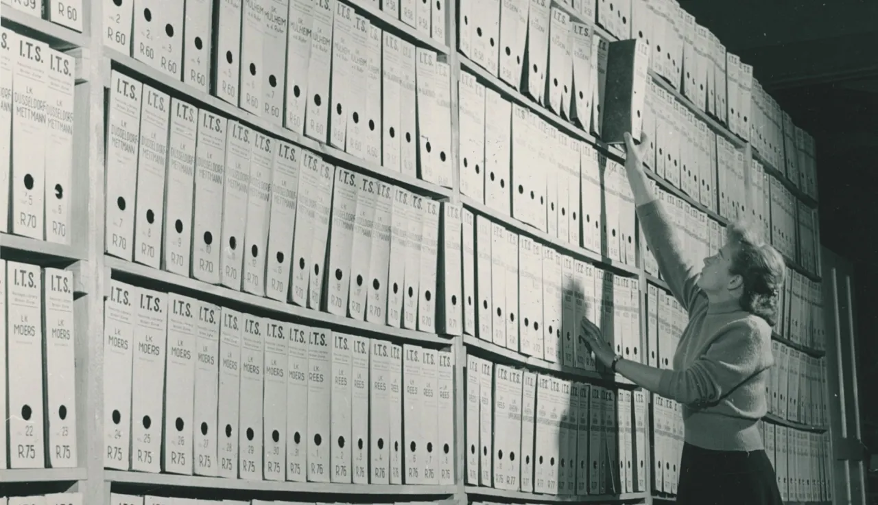 Сотрудница Архивов Арользена достает папку с документами