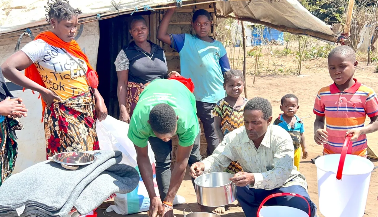 Família de pessoas deslocadas mostra baldes e outros artigos essenciais.