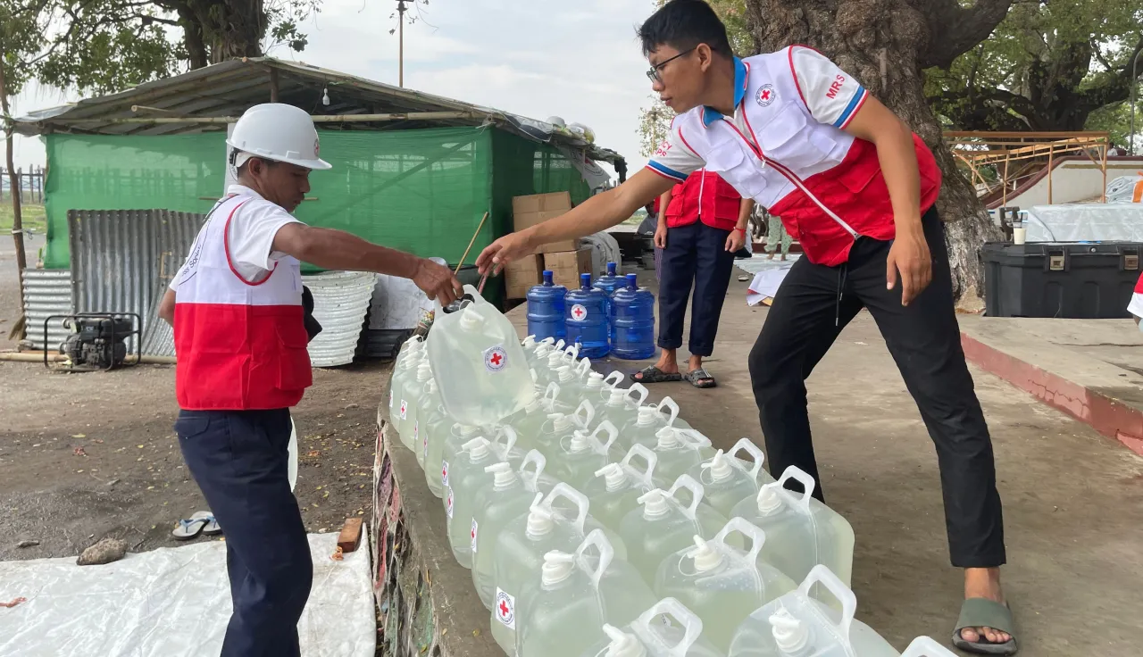 ICRC workers providing clean water containers in Myanmar