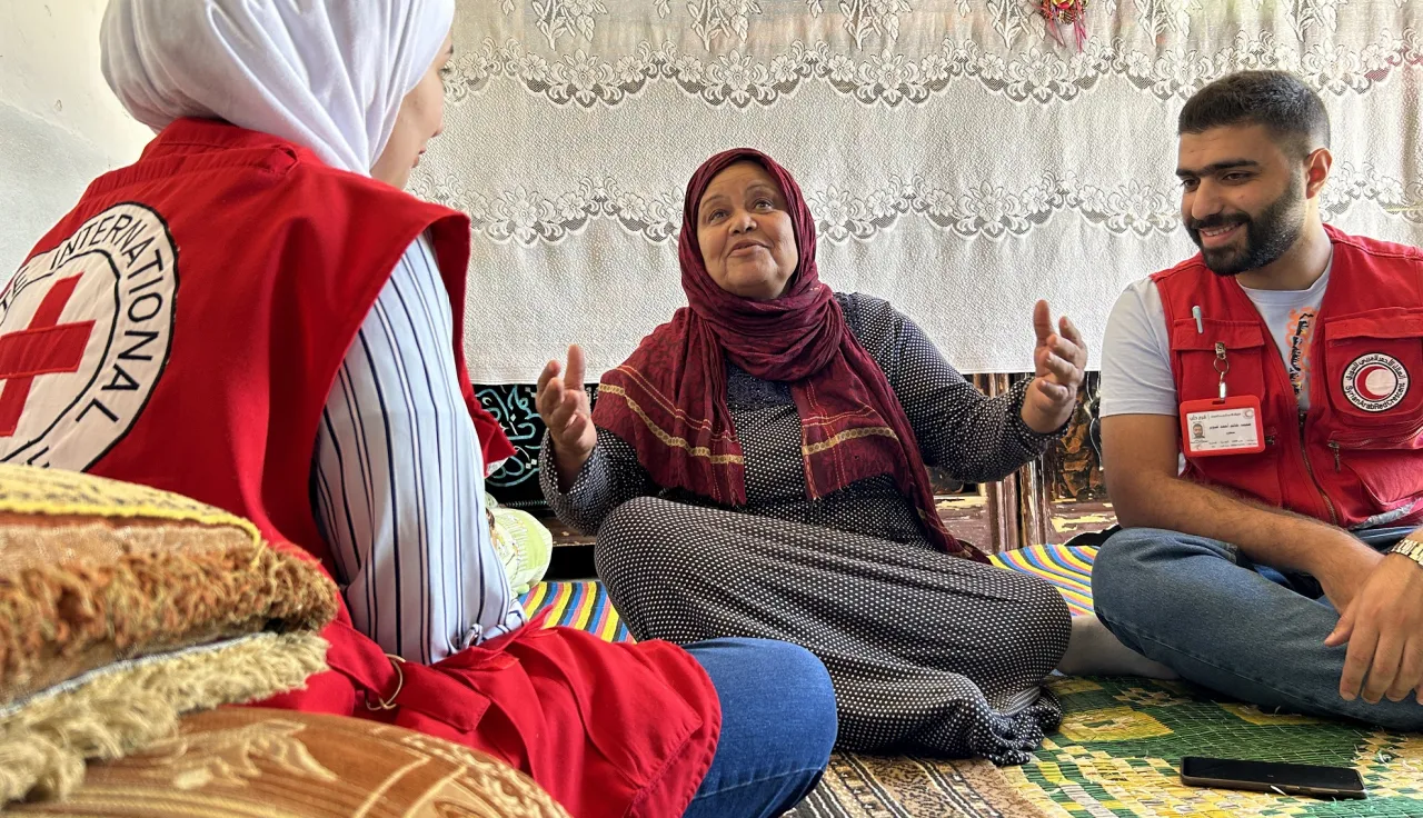 ICRC staff in Aleppo with a woman sitting on the ground