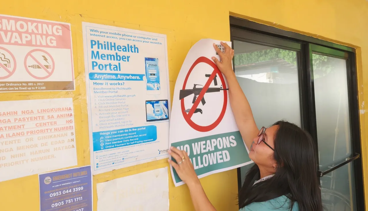 Hospital staff puts up an ICRC-donated poster saying "No weapons allowed"